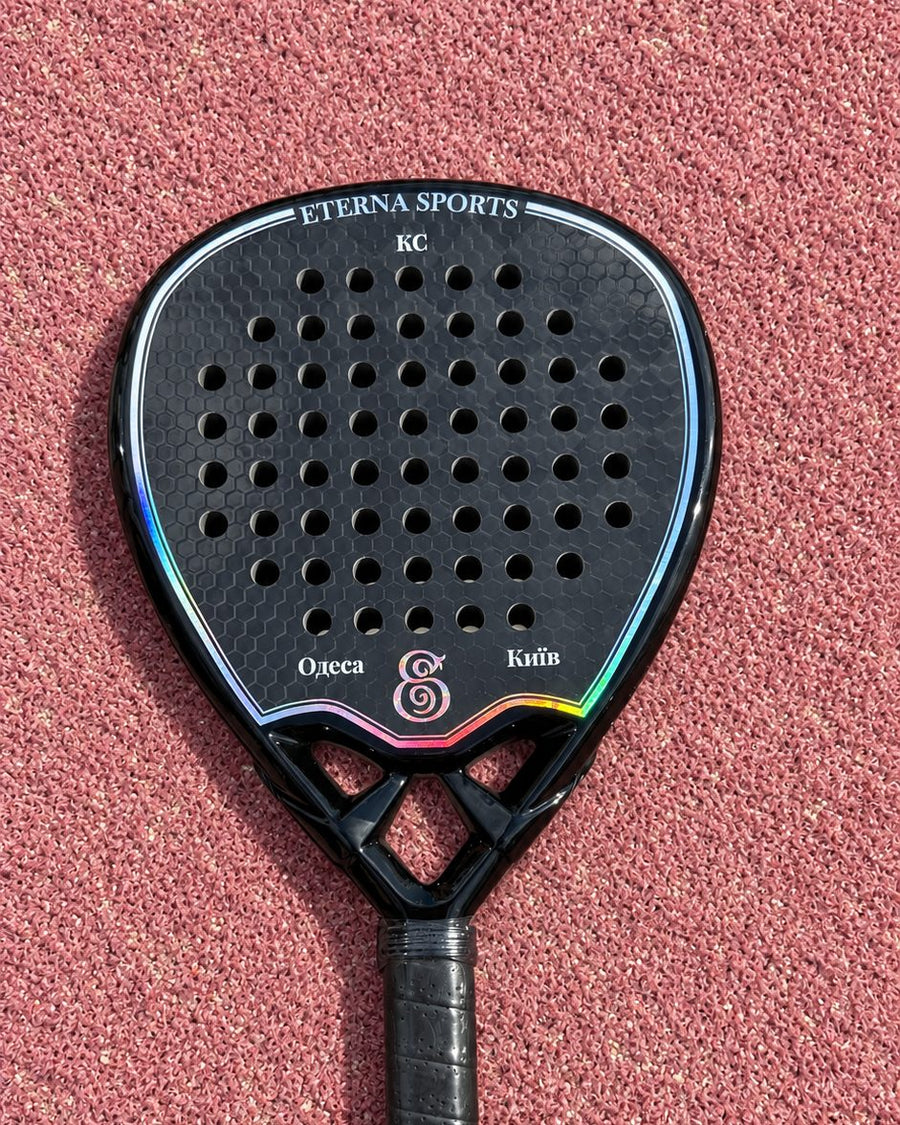 A city name engraved on the left Wing of a Tribeca Laser Black padel racket