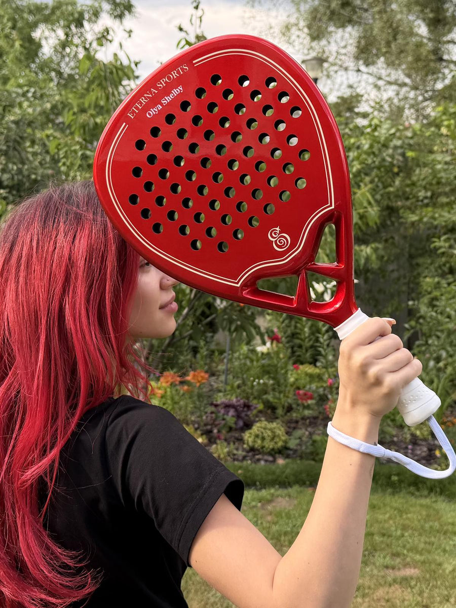Red Eterna Sports racket with the owner's name engraved, held up by its owner