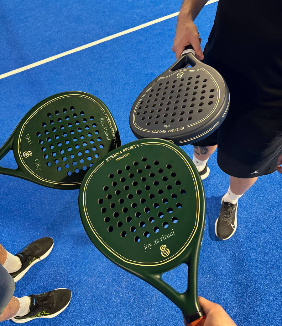 Three personalised Eterna Sports rackets with engraved names, on a padel court
