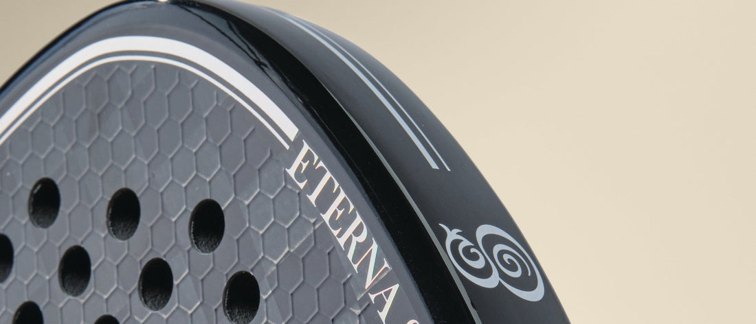 Close-up of the crown of an Eterna Tribeca Laser Black padel racket: honeycomb carbon face, glossy frame edge and the Eterna monogram
