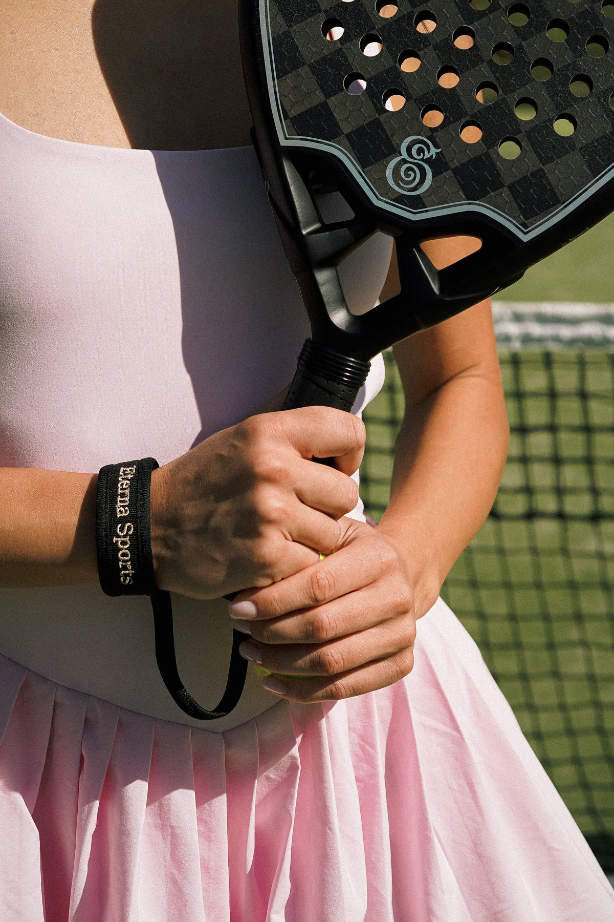 A player holding an Eterna Tribeca Laser Black Matte racket by its handle.