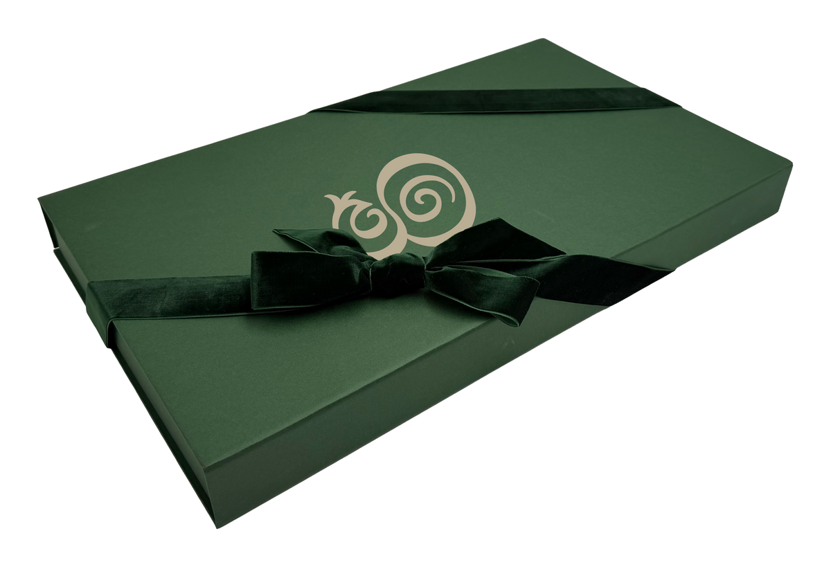 The Eterna gift box — hunter green with the monogram in cream, tied with a velvet ribbon