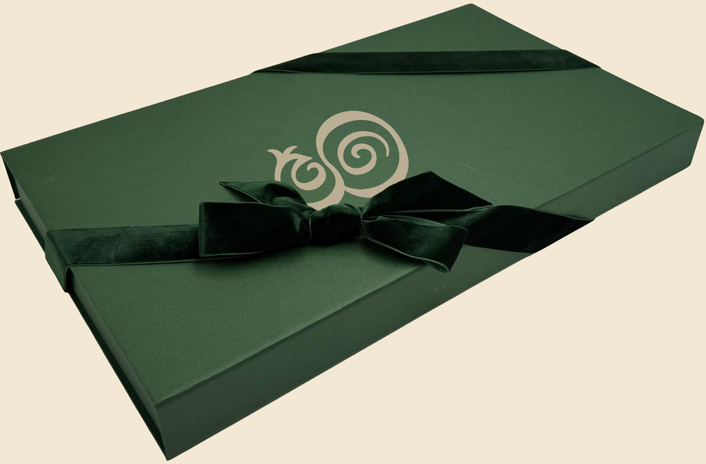 The Eterna gift box — hunter green with the monogram in cream, tied with a velvet ribbon