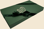 The Eterna gift box — hunter green with the monogram in cream, tied with a velvet ribbon