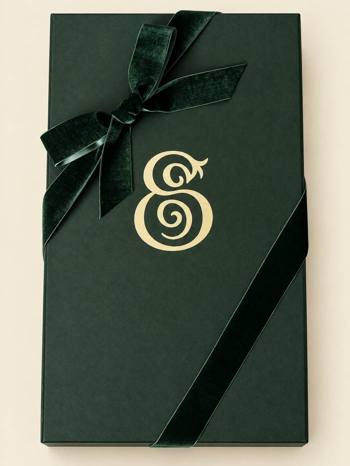 Closed dark green Eterna gift box with a cream monogram and velvet ribbon bow.