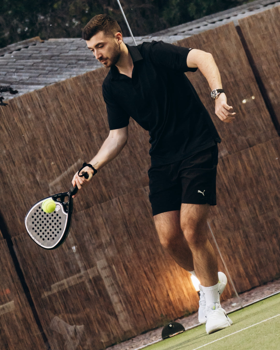 Player mid-rally on a padel court with a black Eterna Sports racket