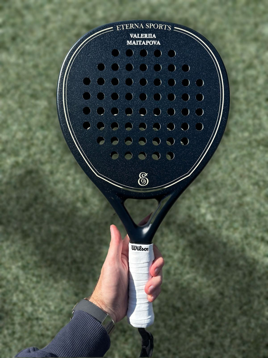 Personalised Eterna Sports racket held up over a padel court
