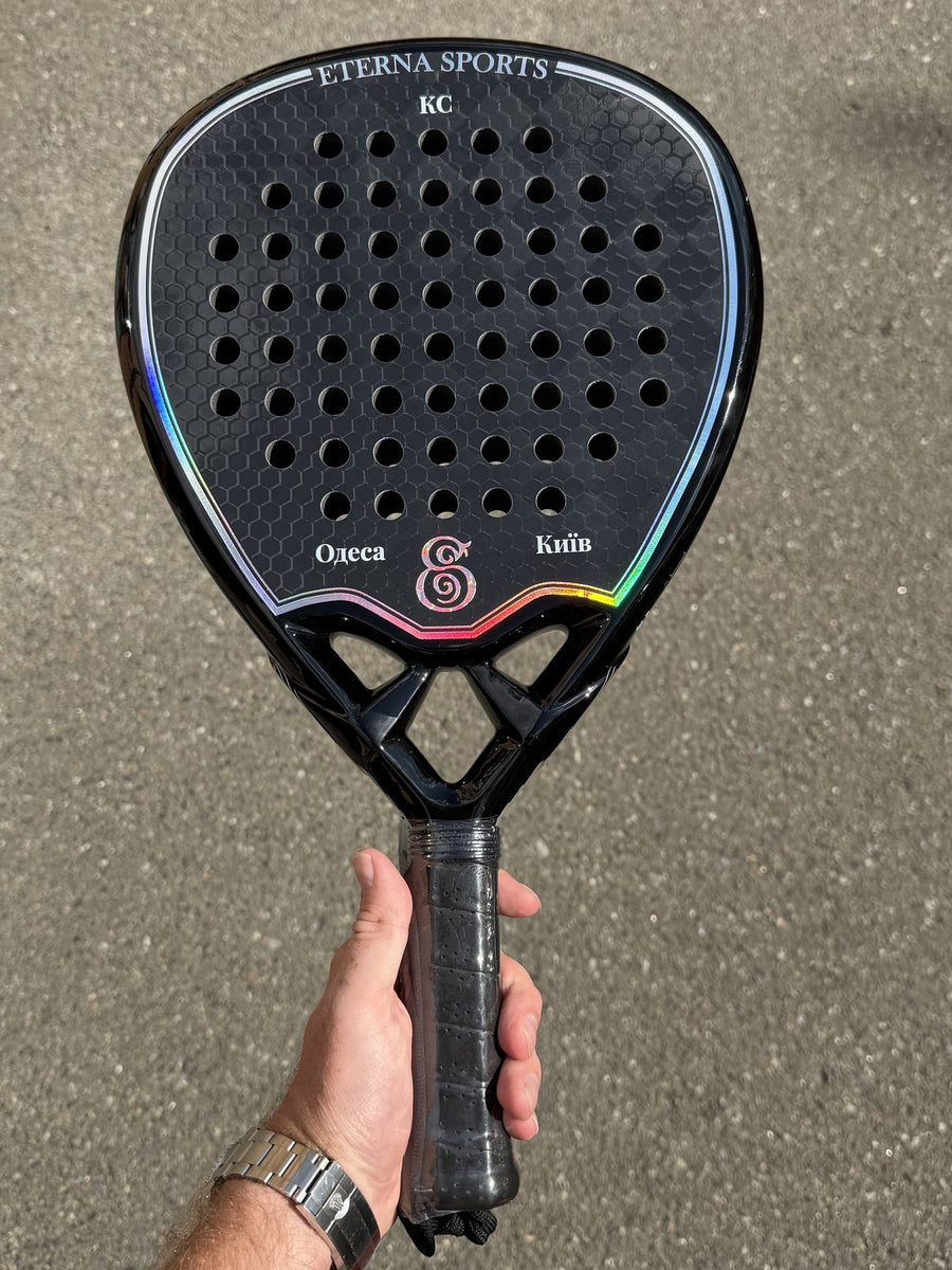 Black Eterna Sports racket engraved with initials and two city names, held on the court